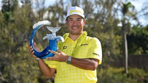 Hideki Matsuyama holding The Sentry trophy.