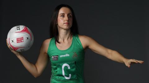 Suzy Drane in Celtic Dragons green top holds a netball in one hand