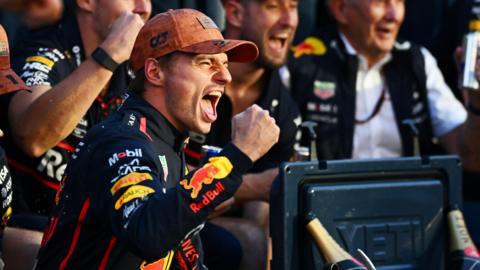 Red Bull's Max Verstappen clenches his fist and yells in celebration with his Red Bull team after winning the United States Grand Prix