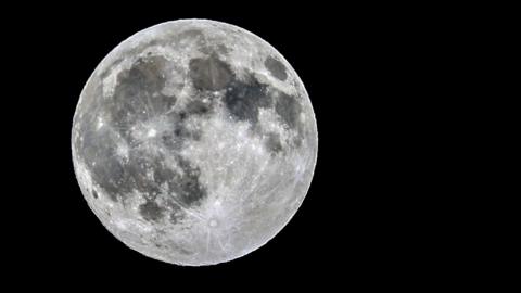 Close up of silver supermoon with visible craters in a black sky