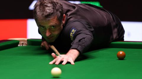 Ronnie O'Sullivan plays a shot