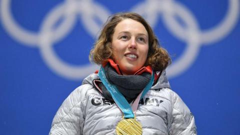 Laura Dahlmeier wearing a gold medal on the podium