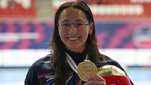 Alice Tai holding a gold medal in her left hand