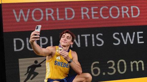 Armand Duplantis stands in front of the world record scoreboard