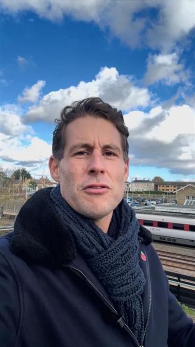 BBC reporter stands in front of train