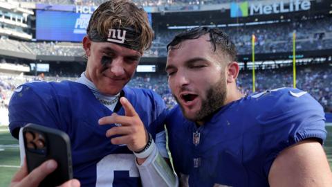New York Giants quarterback Jaxson Dart and running back Cam Skattebo record a video on a smartphone after beating the Los Angeles Chargers
