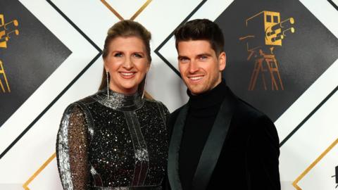 A couple smiling at a red carpet event